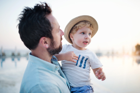 A father holding a toddler boy on beach on summer holiday.の写真素材