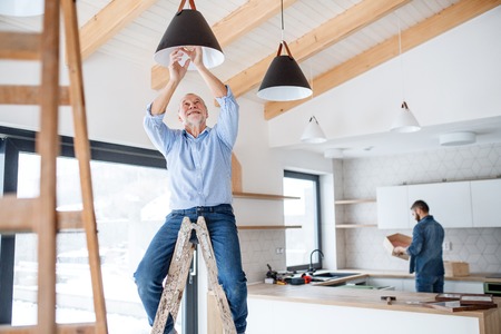 A senior man helping his son with furnishing new house, a new home concept.