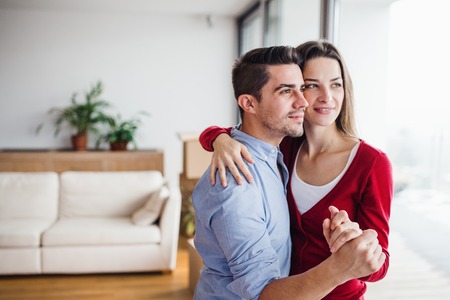Young couple in love standing by the window at home, hugging. Copy space.の写真素材