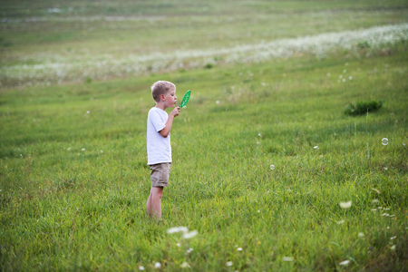 A small boy in nature on a summer day, blowing soap bubbles.の写真素材
