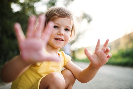 A small cute girl on a road in countryside in sunny summer nature.の写真素材