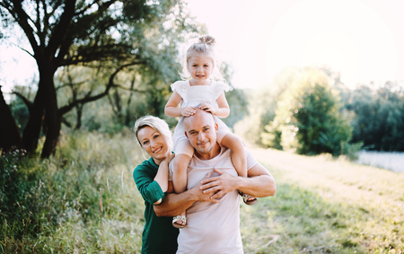 Young family with a small daughter in sunny summer nature.の写真素材