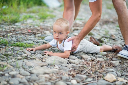 Unrecognizable father lifting a small toddler son in sunny summer nature.の写真素材