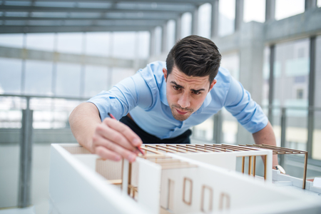 Young businessman or architect with model of a house standing in office, working.の写真素材