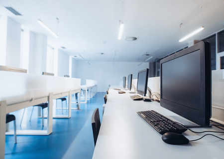 An interior of a modern spacious computer room in a library or office.