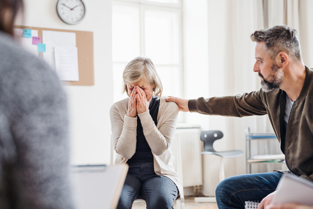 A senior depressed woman crying during group therapy.の写真素材
