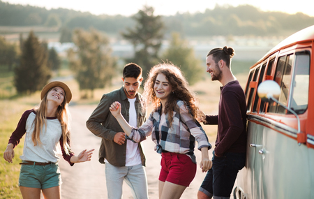 A group of young friends on a roadtrip through countryside, dancing.の写真素材