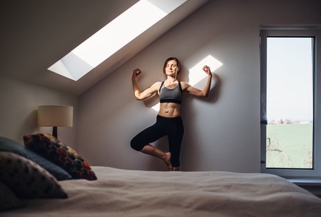 Young woman doing yoga exercise indoors in a bedroom. Copy space.の写真素材