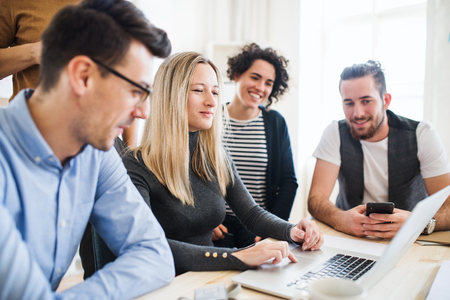 Group of young businesspeople with laptop working together in a modern office.の写真素材