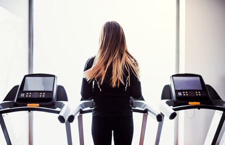 A rear view of young girl or woman doing cardio workout in a gym.の写真素材