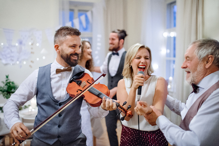 A young bride, groom and other guests dancing and singing on a wedding reception.の写真素材