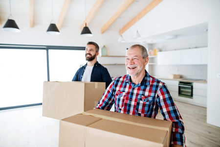 A senior man helping his son with furnishing new house, a new home concept.の写真素材