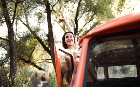 A young girl on a roadtrip through countryside, waving at somebody from a car.の写真素材