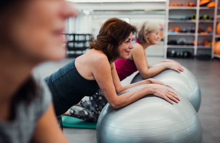 Group of cheerful female seniors in gym doing exercise on fit balls.の写真素材