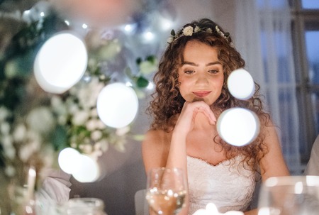 A front view of a young bride sitting at a table on a wedding.の写真素材