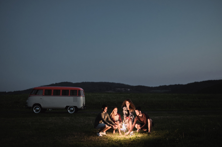 A group of friends with sparklers standing outdoors at dusk.の写真素材