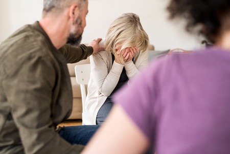A senior depressed woman crying during group therapy.
