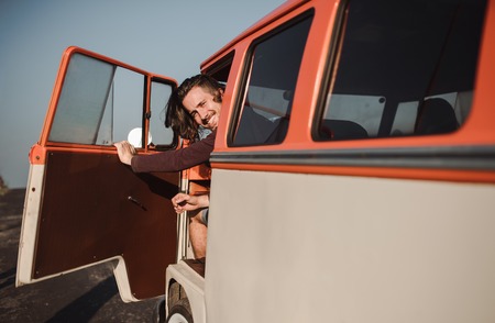 A young man getting out of a car on a roadtrip through countryside. Copy space.の写真素材