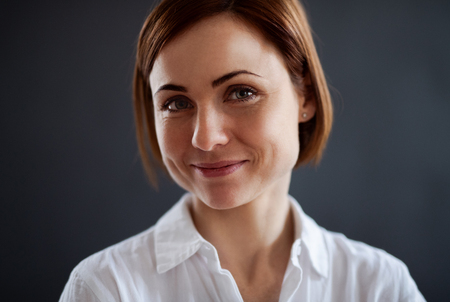 A portrait of young beautiful woman standing against dark background.の写真素材