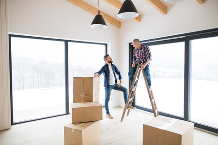 A mature man with his senior father furnishing new house, a new home concept.の写真素材