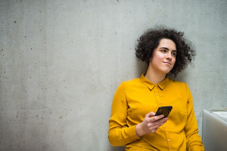 Young student or businesswoman with smartphone in a library or office.の写真素材