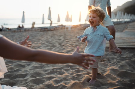 Young family with toddler boy having fun on beach on summer holiday.の写真素材