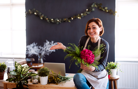 Young creative woman in a flower shop. A startup of florist business.の写真素材