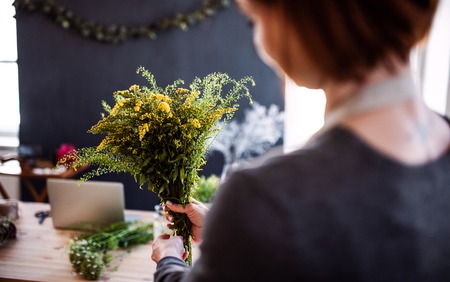 Midsection of young creative woman in a flower shop. A startup of florist business.の写真素材