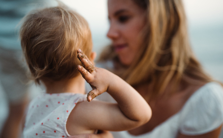 Close-up of young mother with a toddler girl on beach on summer holiday.の写真素材