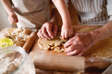 Midsection of grandmother with small toddler boy making cakes at home.の写真素材