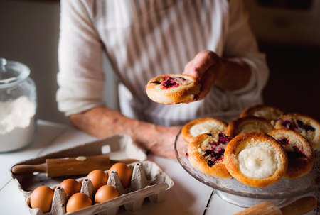 A midsection of senior grandmother making and holding cakes at home.の写真素材