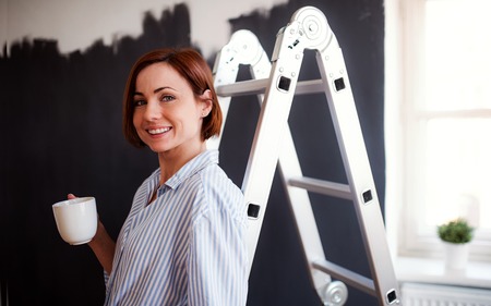 A portrait of young woman painting wall black. A startup of small business.の写真素材