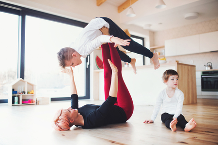 A young woman with two children playing on the floor, having fun.の写真素材