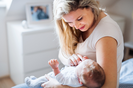 A beautiful young mother with a newborn baby at home.の写真素材