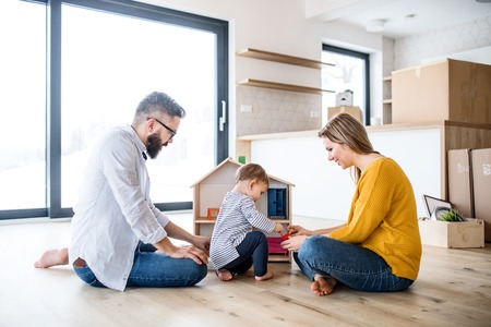 A portrait of young family with a toddler girl moving in new home, playing.の写真素材