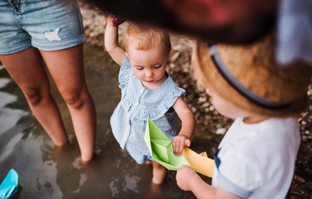 A midsection of family with two toddler children outdoors by the river in summer.の写真素材