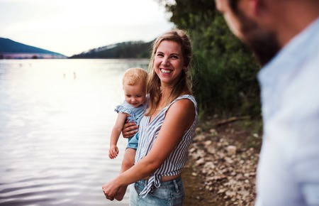 A mother with a toddler daughter outdoors by the river in summer.の写真素材
