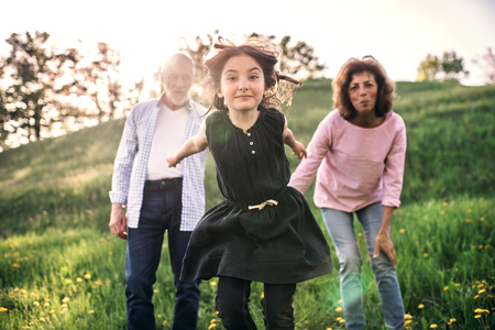 Senior couple with granddaughter outside in spring nature.の写真素材