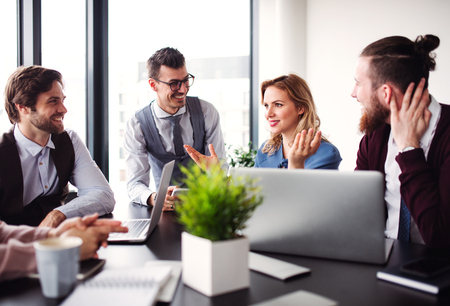 A group of young business people sitting in an office, having meeting.
