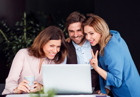 A group of business people sitting in an office, using laptop.の写真素材