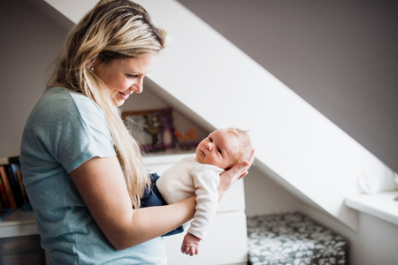 A beautiful young mother with a newborn baby at home.の写真素材