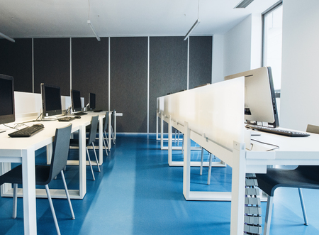 An interior of a modern spacious computer room for students in a library or office.