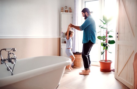 Small girl with young father in bathroom at home, having fun.の写真素材