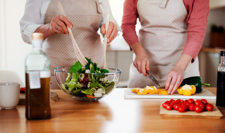 A midsection of women at home, preparing vegetable salad.の写真素材