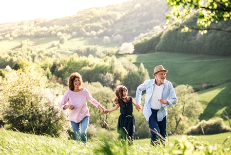 Senior couple with granddaughter on a walk outside in spring nature.の写真素材