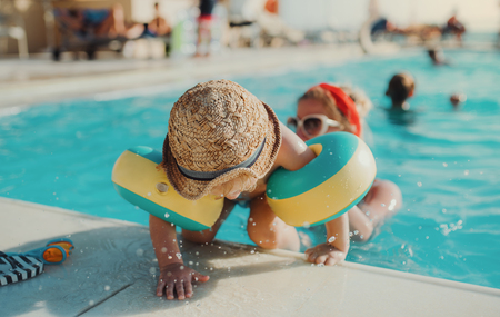 A small toddler boy with armbands and mother swimming in water on summer holiday.の写真素材