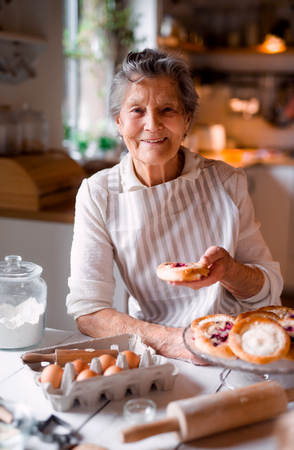 Elderly woman making cakes in a kitchen at home.の写真素材