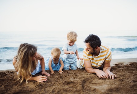 A family with two toddler children lying on sand beach on summer holiday.の写真素材