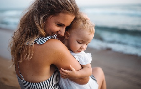 Close-up of young mother with a toddler girl on beach on summer holiday.の写真素材