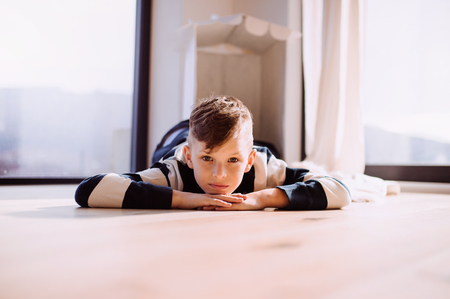 A small boy lying indoors on the floor at home. Copy space.の写真素材